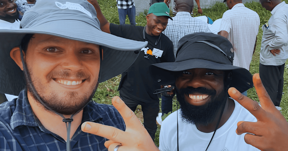 Farmers and volunteers smiling at outdoor agricultural event.