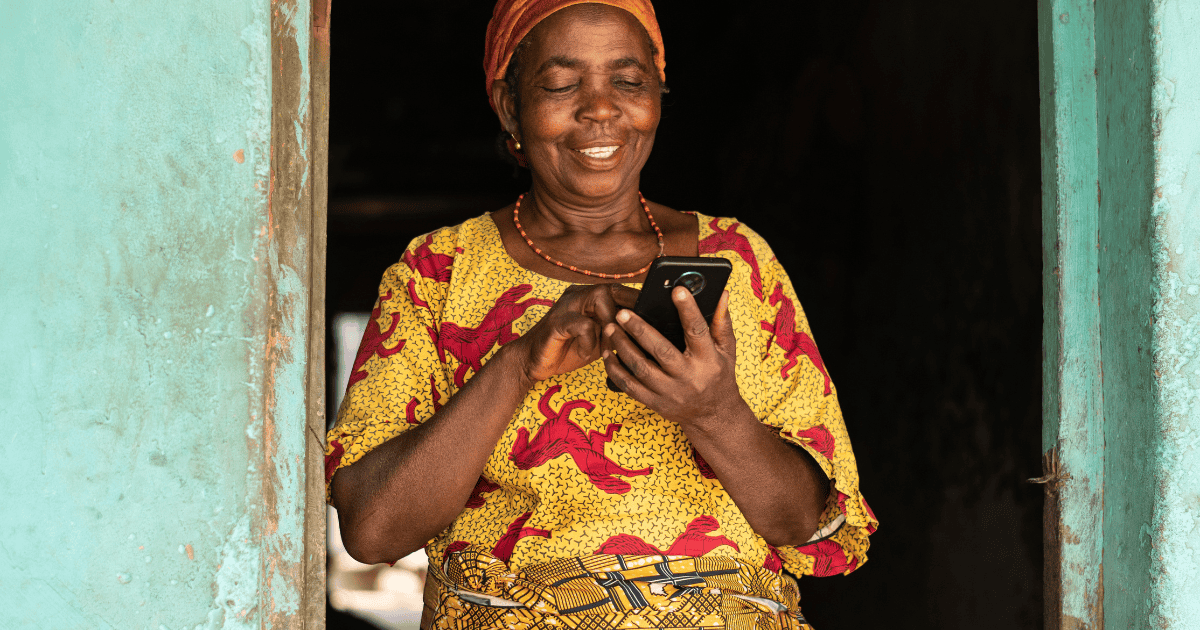 Farmer woman smiling while using a smartphone at her home.